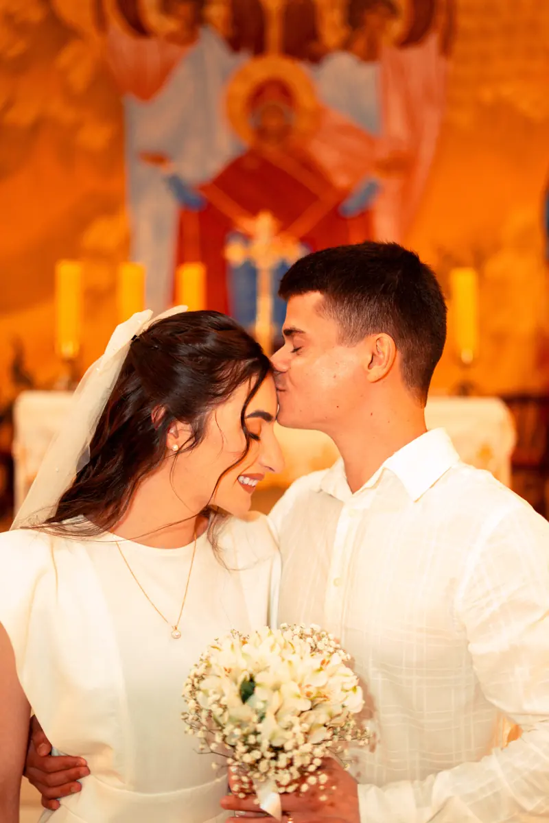 Noivos se beijando com buquê de flores brancas