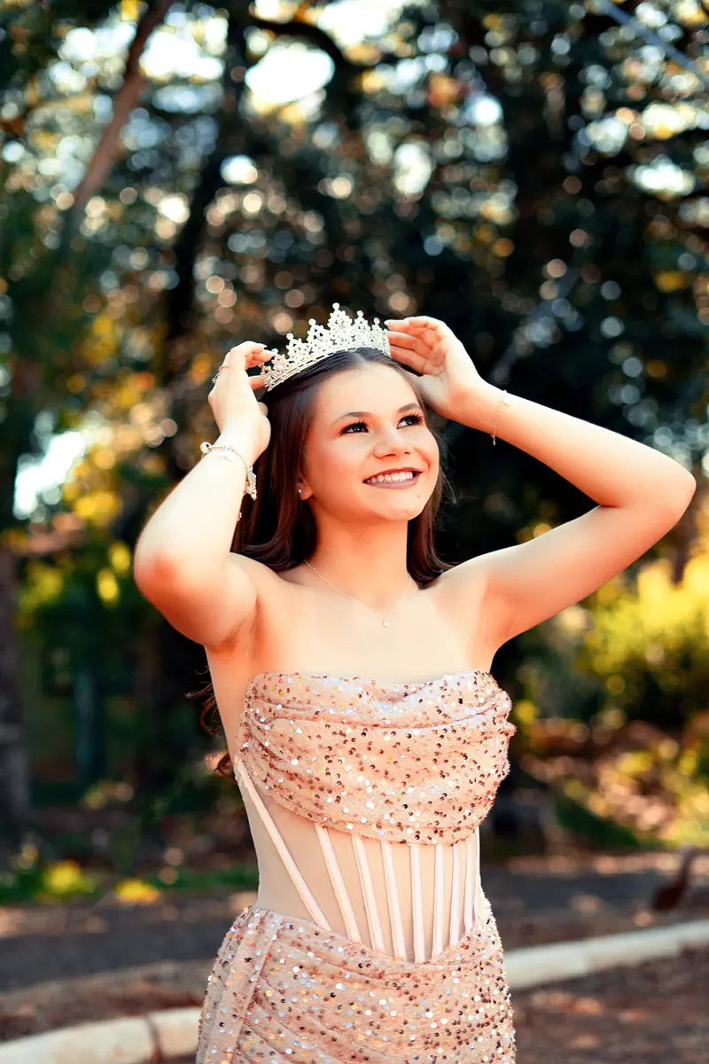 Debutante ajeitando a coroa, luz suave entre as árvores